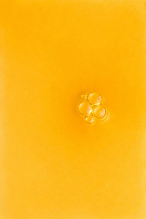 Golden serum texture with visible bubbles, likely vitamin C skincare, unboxed close-up.