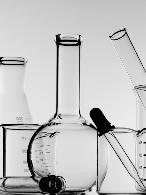 Clear glass laboratory bottles and pipette, highlighting clinical skincare ingredients packaging